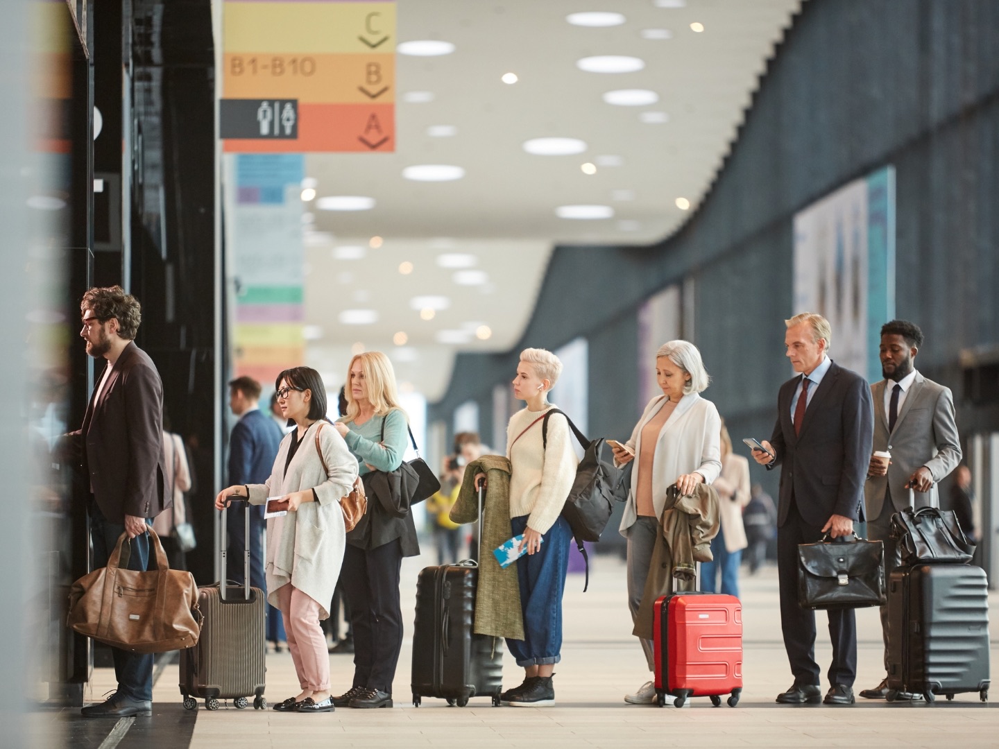 Travelers waiting with luggage at an airport during a changing itinerary