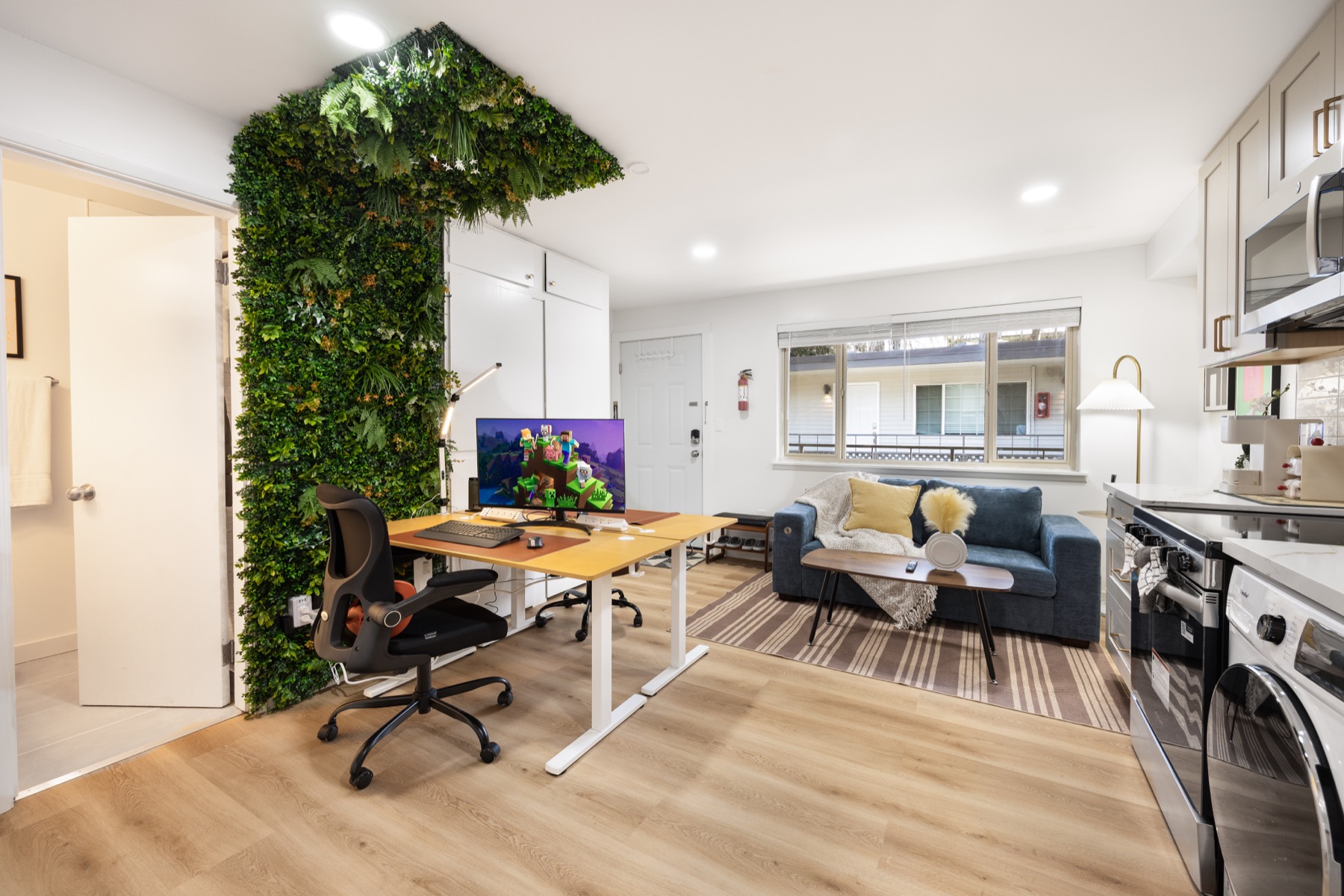 A work-ready Seattle apartment hotel studio with a desk, couch, kitchenette, and green wall.