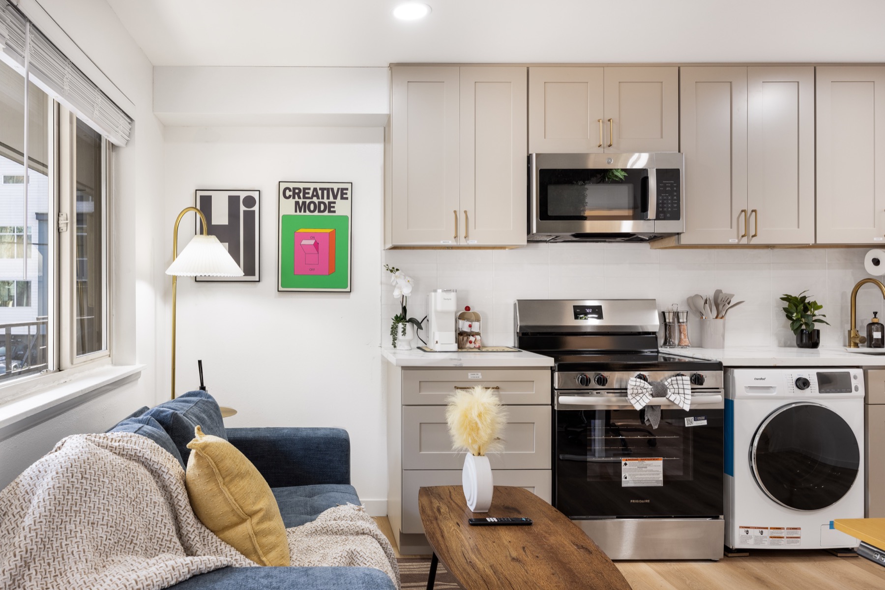 A compact Seattle apartment hotel studio with a couch, kitchenette, stove, microwave, and in-unit laundry.